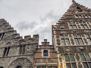 Stone and brick building with elaborate facades under a cloudy sky, Ghent, Belgium, Europe