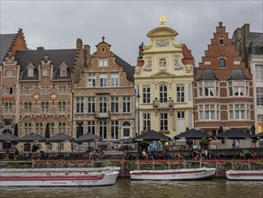 Historic buildings and cafés along a canal with boats on the banks, Ghent, Belgium, Europe