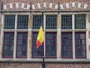 Six windows with Belgian flag on a brick façade, symbolising historical architecture, Ghent,