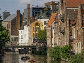 A city canal with boats and old buildings along the water in summer weather, Ghent, Belgium, Europe