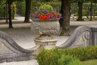 A decorative stone flowerpot with colourful flowers in a garden park, Salzburg, Austria, Europe