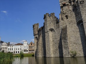 Massive medieval castle on the banks of a canal on a sunny day, Ghent, Belgium, Europe
