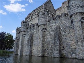 Mighty medieval castle made of grey stone with high walls and a surrounding moat, Ghent, Belgium,