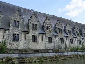 Medieval building with several small windows along a river, Ghent, Belgium, Europe