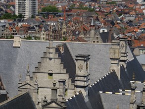 Close-up of roofs and chimneys of historic buildings framed by modern structures in the distance,