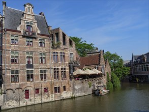Brick houses and a cosy café on a canal surrounded by green trees, Ghent, Belgium, Europe