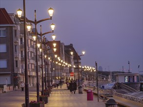 A promenade at dusk, illuminated by lanterns, people strolling along, quiet and peaceful