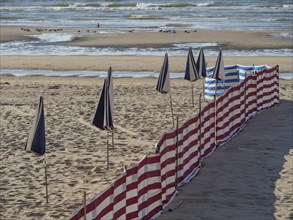 Striped windbreaks on the sandy beach with erected, closed parasols, de haan, Belgium, Europe