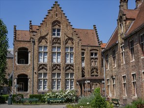 A historic building with ornate windows and entrances, set in a garden, Bruges, Belgium, Europe