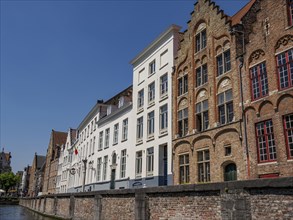 Historic brick and plaster facades along a canal under a blue sky, Bruges, Belgium, Europe