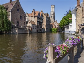 Idyllic view of a medieval river with historic buildings and flowers on a bridge, Bruges, Belgium,