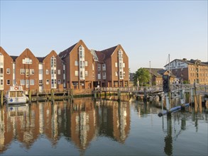 Brick houses radiating tranquillity and a jetty are reflected in the water of the canal, the sky is