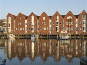 Red brick facades and boats in the harbour reflected in the water in the evening sun,