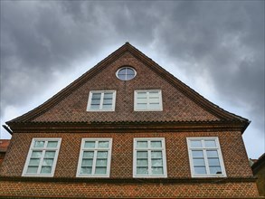 A brick house with large windows and a pointed roof under a gloomy sky, Eckernforde,