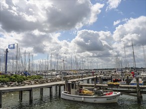 A boat in the foreground in the harbour, background dominated by masts and clouds, Maasholm,