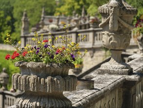Blooming flowers in a stone flower pot on a historic railing, bright colours and vibrant nature in