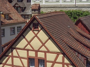 Close-up of the roofs of several half-timbered houses with tiles and windows in a historic
