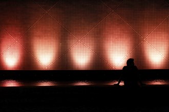 Man sitting in front of illuminated house in Hong Kong