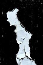 A piece of torn and cracked white paint set against a black background, highlighting aged textures,