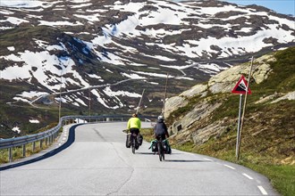 Cyclists on mountain crossing Sognefjellsvegen, mountain pass over the Sognefjellet, touristic