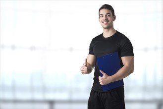 Personal trainer in a gym holding a notepad