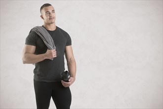 Man holding a protein shake after a workout in the gym, isolated in grey