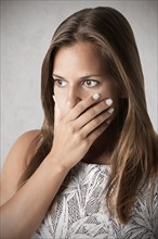 Closeup of a concerned woman covering her mouth, in a dark mood