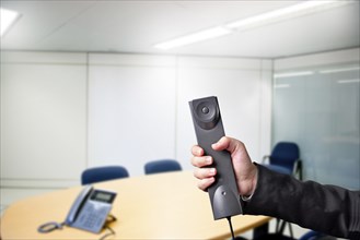 Casual business person holding a phone in a meeting room