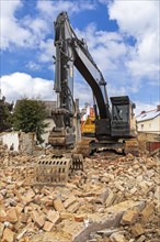 Excavator on the rubble of a demolished building