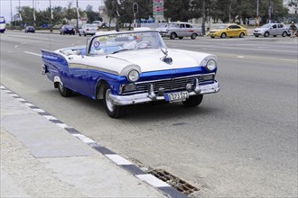 Havana, Cuba, Central America, A blue and white vintage car drives along a city street, Central
