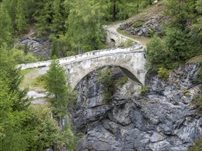 Historic bridge over narrow gorge just below water dam Barrage de Mauvoisin, Val de Bagnes,