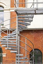 Metal spiral staircase on the brick façade of a refurbished industrial building