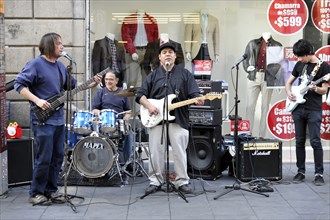 Mexico City, Mexico, Central America, Four street musicians play live music in front of a shop