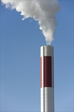 White smoke out of a smokestack in front of blue sky