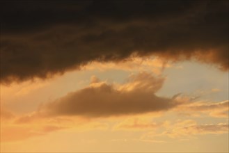 Cloudy sky at sunset. The sky is visible through a gap in the clouds. The image conveys a mood of