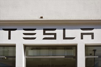 Heidelberg, Germany, June 28th 2024: Tesla electric car brand logo above showroom store in city