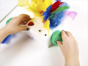 Little girls hands playing with colorful feathers, creating Easter decoration