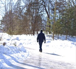 Person walking up a icy road at winter, strong sunlight