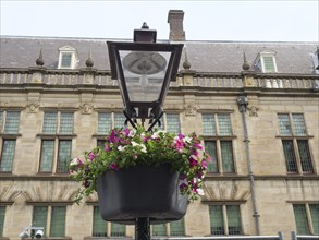 Flower basket on a historic black lantern in front of an old sandstone building, Leiden,