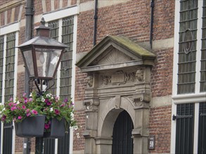 Historic façade with hanging flower baskets and an ornate lantern in the foreground, Leiden,