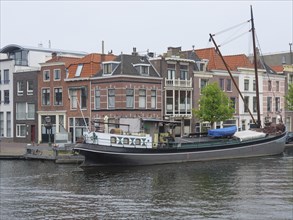 Boat on a canal next to gabled houses in a Dutch town, Leiden, Netherlands