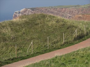 A grassy hill with a hiking trail along the coast, helgoland, germany