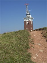 A lighthouse stands on a grassy hill under a clear blue sky, helgoland, germany