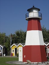 Red and white lighthouse, colourful houses and flags on a green lawn under a blue sky, helgoland,