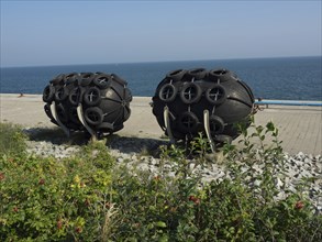 Black round fenders on the shore next to the blue sea under the clear sky, helgoland, germany