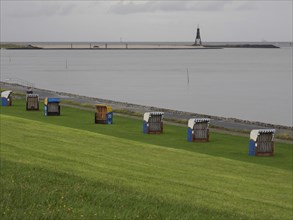 Beach chairs on a green meadow near the sea, with a beacon in the background, cuxhaven, germany