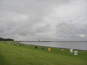 Colourful beach chairs on a large meadow next to the sea under an overcast sky, cuxhaven, germany