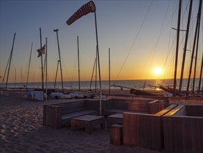 Sailboats and empty seats on the beach at sunset with calm sea and sandy bottom, De Haan, Flanders,