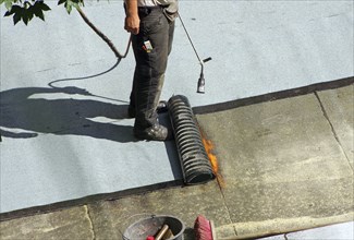 Roofer with a gas burner on a roof