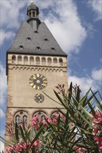 Gothic clock tower with floral decorations in the foreground, blue sky with clouds, speyer, germany
